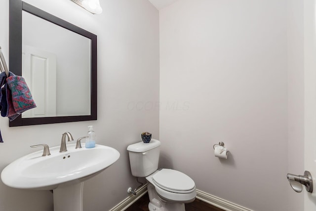 bathroom featuring toilet, baseboards, and a sink