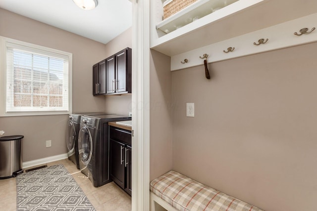 washroom with visible vents, baseboards, washing machine and clothes dryer, light tile patterned flooring, and cabinet space