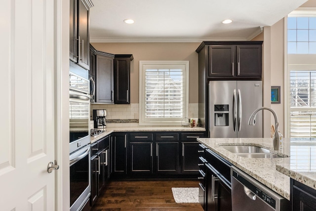 kitchen with dark wood-type flooring, ornamental molding, a sink, backsplash, and appliances with stainless steel finishes