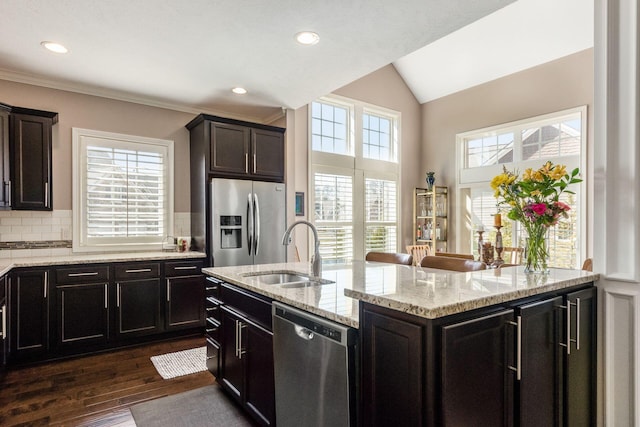 kitchen with light stone countertops, dark wood-style flooring, a sink, decorative backsplash, and appliances with stainless steel finishes