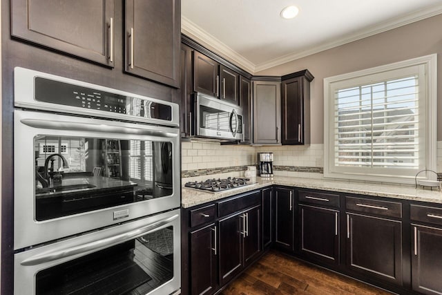 kitchen featuring light stone countertops, dark wood finished floors, ornamental molding, decorative backsplash, and stainless steel appliances