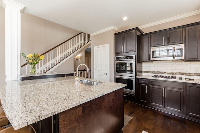 kitchen featuring dark wood-type flooring, a sink, tasteful backsplash, appliances with stainless steel finishes, and light stone countertops