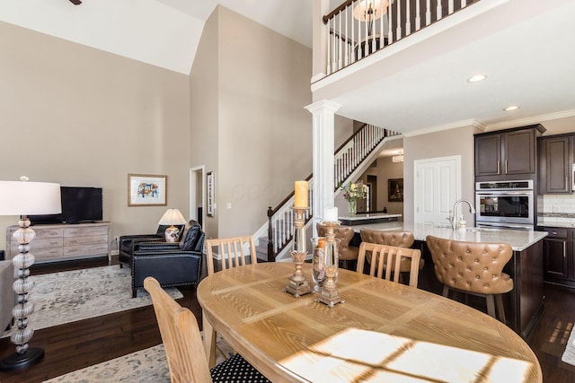 dining room with stairway, dark wood finished floors, decorative columns, recessed lighting, and crown molding