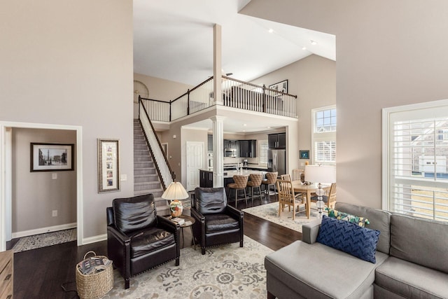 living room with stairway, baseboards, high vaulted ceiling, and wood finished floors