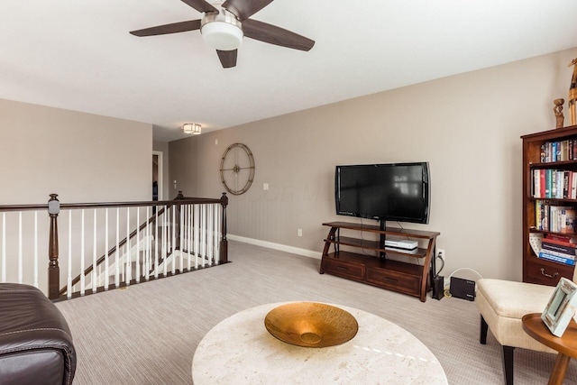 living area featuring baseboards, an upstairs landing, ceiling fan, and carpet flooring