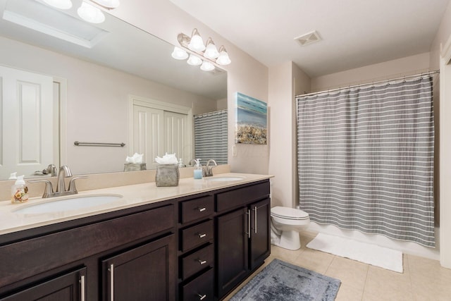 bathroom featuring tile patterned floors, double vanity, toilet, and a sink