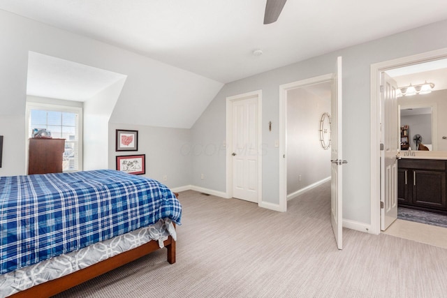 bedroom featuring light colored carpet, ensuite bath, baseboards, and vaulted ceiling