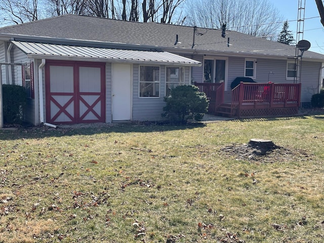 rear view of house featuring a lawn and a shingled roof