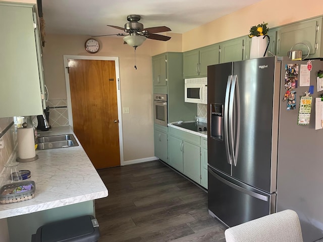 kitchen with green cabinetry, light countertops, stainless steel appliances, a ceiling fan, and a sink