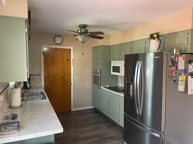 kitchen with a ceiling fan, light countertops, appliances with stainless steel finishes, green cabinets, and tasteful backsplash