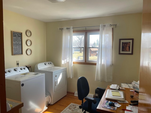 clothes washing area with baseboards, light wood-style floors, and washer and clothes dryer