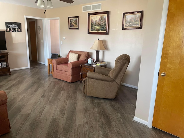 sitting room with visible vents, baseboards, dark wood-style floors, and a ceiling fan