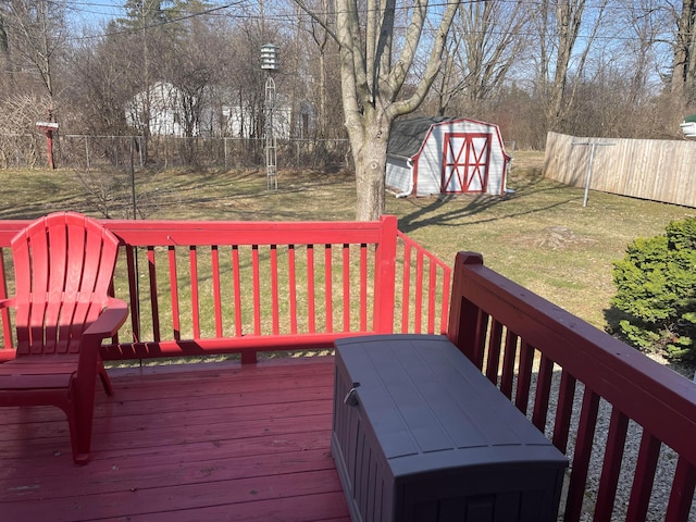 wooden deck featuring an outbuilding, a shed, a yard, and fence