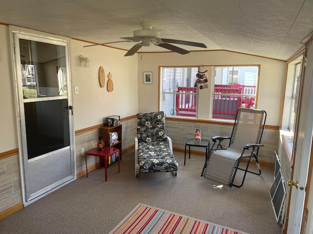 living area with a wainscoted wall, ceiling fan, and vaulted ceiling