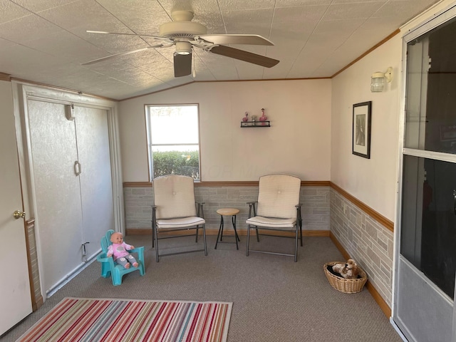 sitting room featuring carpet flooring, wainscoting, crown molding, lofted ceiling, and ceiling fan