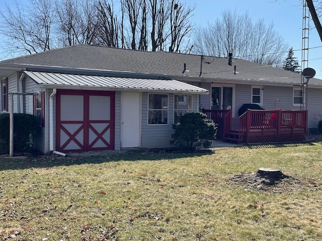 rear view of property featuring a deck, a lawn, and roof with shingles