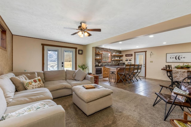 living room with indoor wet bar, recessed lighting, french doors, tile patterned floors, and a textured ceiling