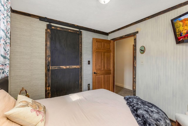 carpeted bedroom with a barn door and crown molding