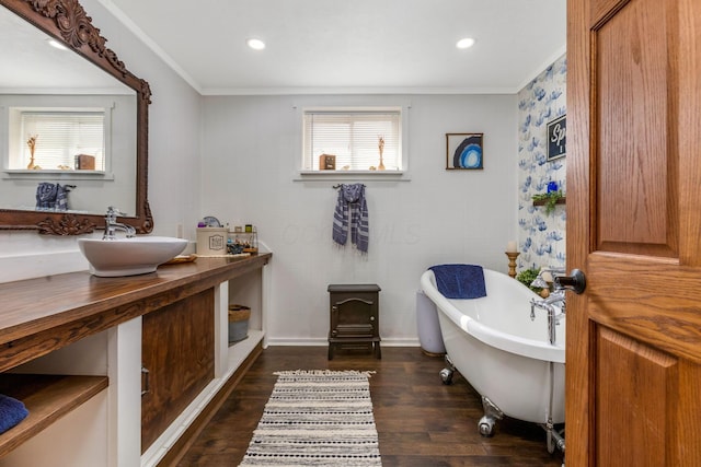 bathroom featuring crown molding, recessed lighting, wood finished floors, a soaking tub, and a sink