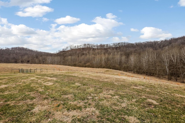 exterior space with a rural view, fence, and a view of trees