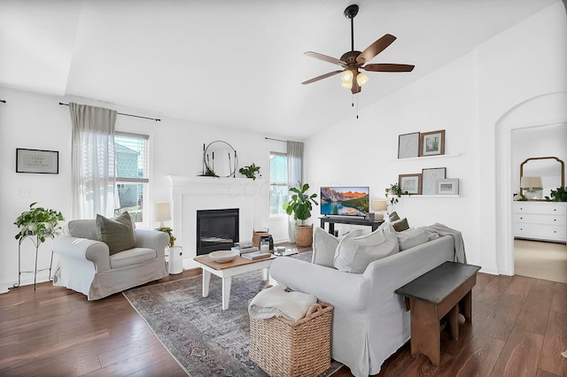 living room with dark wood finished floors, a glass covered fireplace, high vaulted ceiling, and ceiling fan