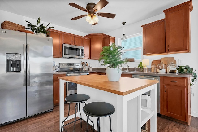 kitchen with a center island, a kitchen breakfast bar, dark wood-style floors, stainless steel appliances, and a sink