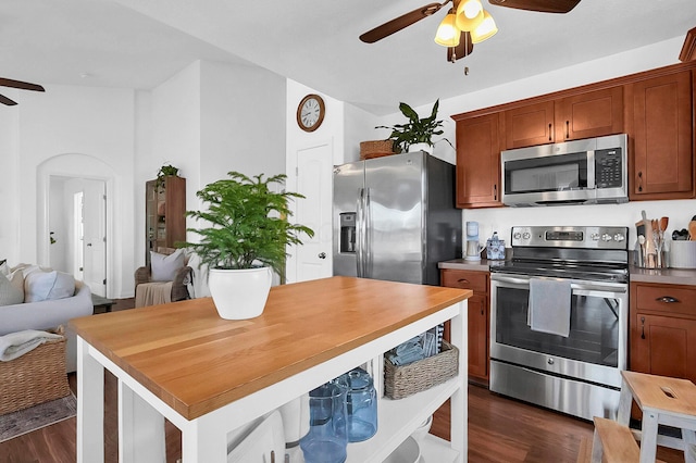 kitchen with open floor plan, appliances with stainless steel finishes, brown cabinetry, ceiling fan, and dark wood-style flooring