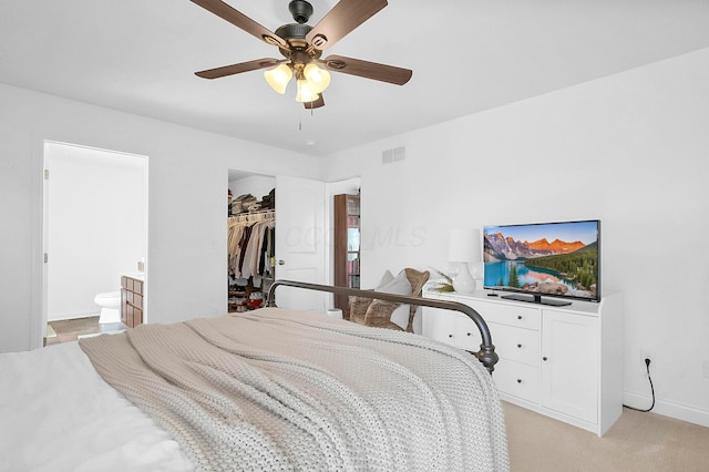 bedroom featuring visible vents, a walk in closet, connected bathroom, light colored carpet, and ceiling fan