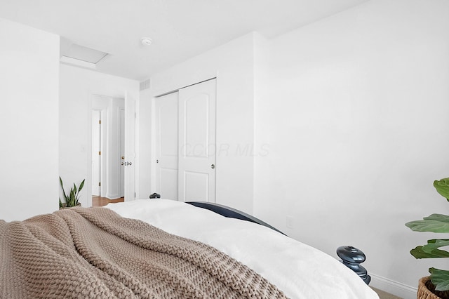 bedroom with a closet, visible vents, attic access, and baseboards