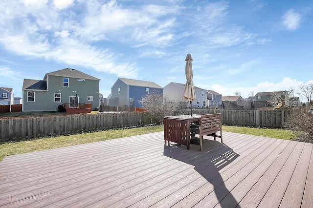 wooden deck featuring outdoor dining space, a yard, a fenced backyard, and a residential view