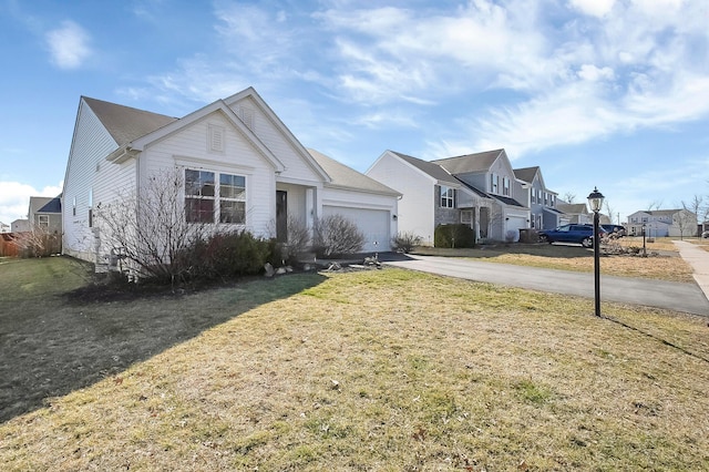 view of front of property featuring a residential view, driveway, a front lawn, and a garage