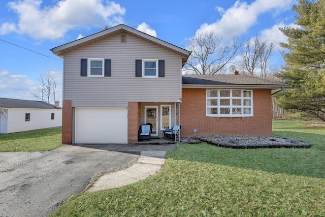 tri-level home with a garage, a front yard, brick siding, and driveway