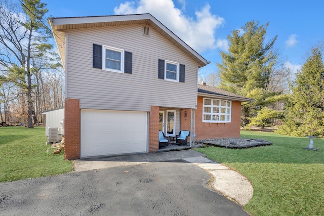 tri-level home featuring a front yard, a garage, brick siding, and aphalt driveway