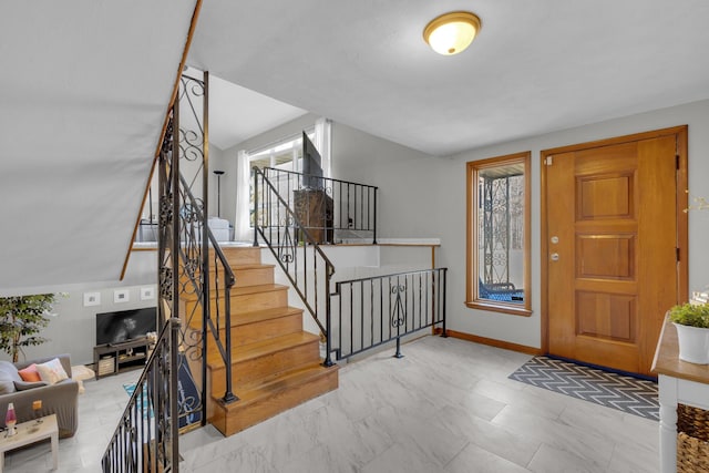 foyer entrance with marble finish floor, stairs, and baseboards