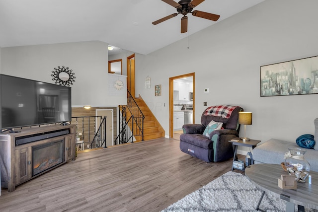 living room with ceiling fan, wood finished floors, stairs, and vaulted ceiling