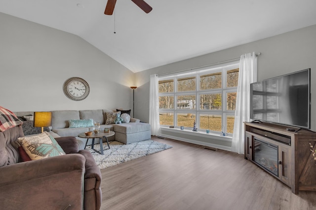 living room featuring visible vents, lofted ceiling, wood finished floors, and a ceiling fan