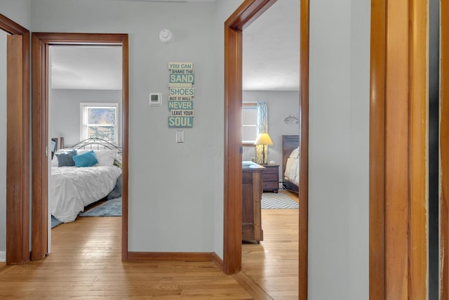 hall with light wood-style flooring and baseboards