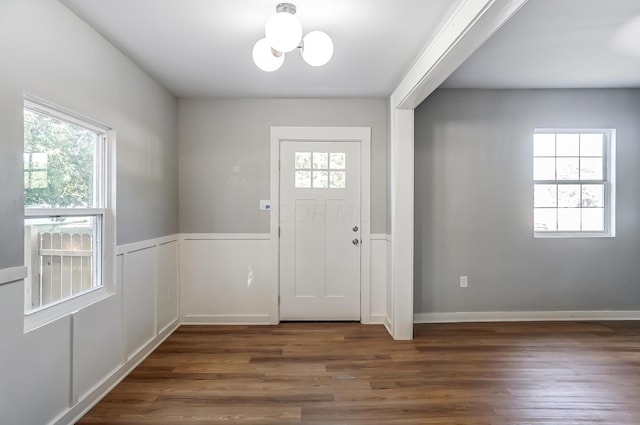 foyer entrance with a chandelier, a wainscoted wall, and wood finished floors