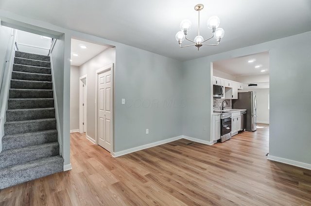 interior space featuring light wood finished floors, appliances with stainless steel finishes, a chandelier, and light countertops