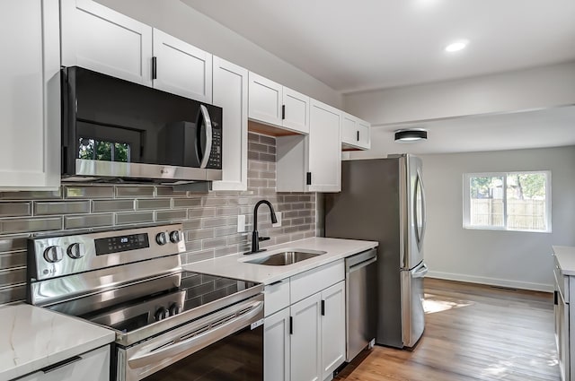 kitchen featuring a sink, stainless steel appliances, tasteful backsplash, and white cabinetry