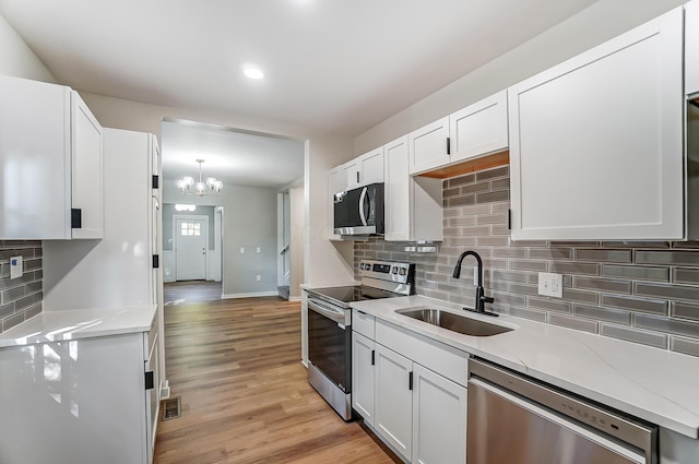 kitchen with a sink, stainless steel appliances, white cabinets, and light countertops