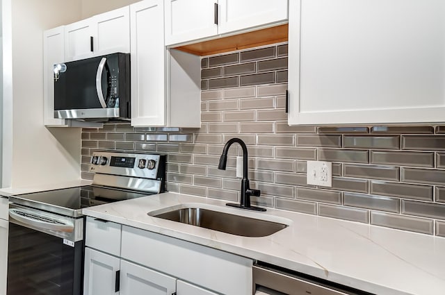 kitchen featuring a sink, decorative backsplash, appliances with stainless steel finishes, and white cabinetry