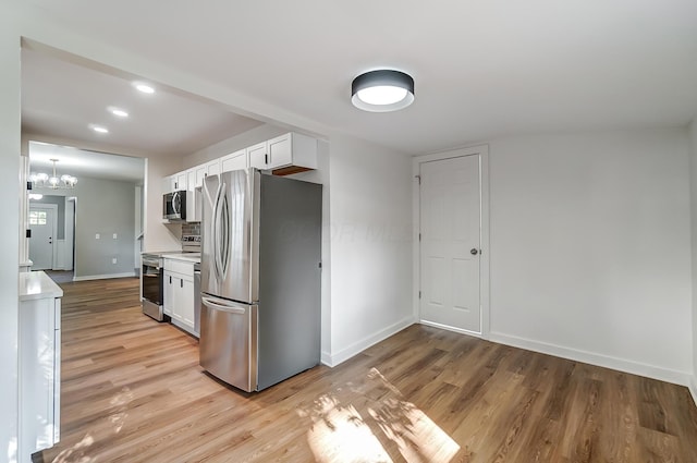 kitchen featuring light countertops, white cabinets, light wood-style flooring, and appliances with stainless steel finishes