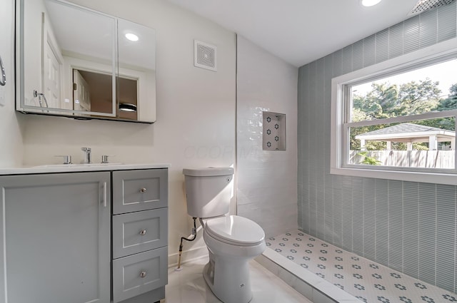 bathroom featuring vanity, baseboards, visible vents, tiled shower, and toilet