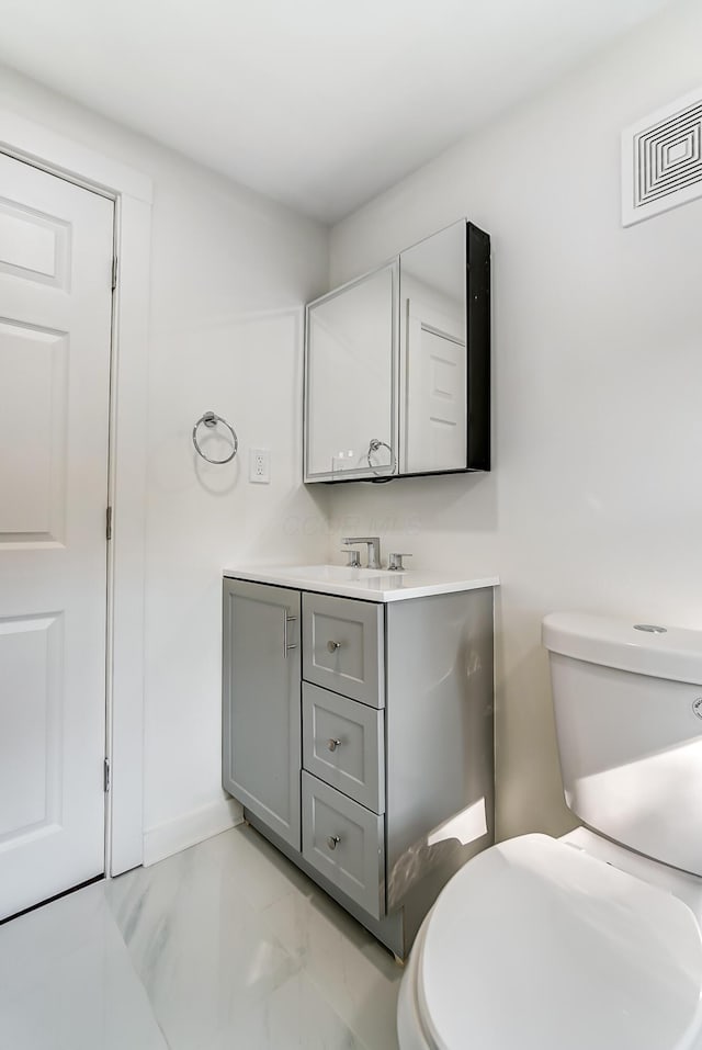 half bathroom featuring vanity, baseboards, visible vents, toilet, and marble finish floor