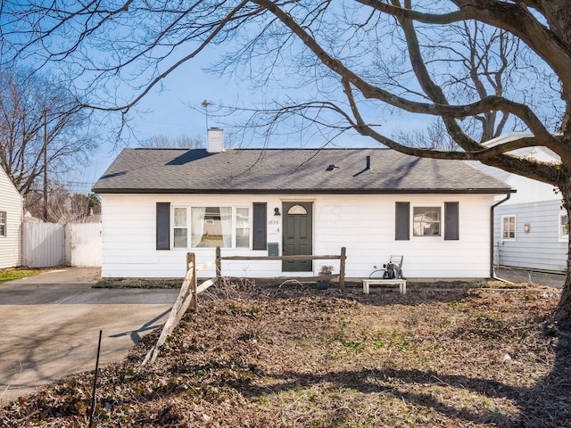 ranch-style house with fence, roof with shingles, and a chimney