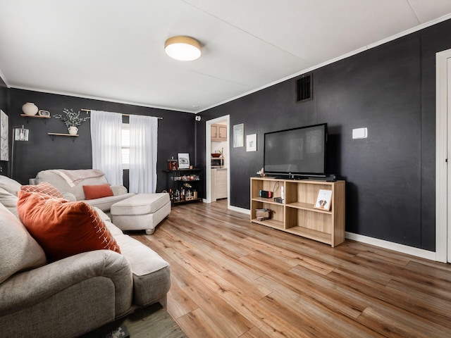 living room with visible vents, baseboards, wood finished floors, and ornamental molding