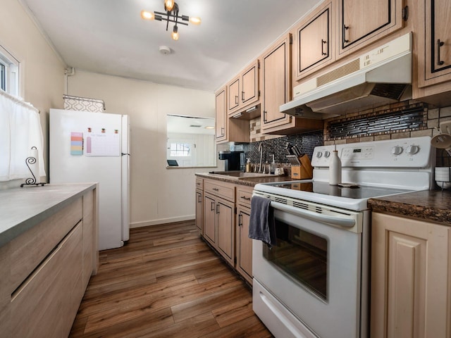 kitchen featuring white appliances, dark wood finished floors, a sink, decorative backsplash, and dark countertops