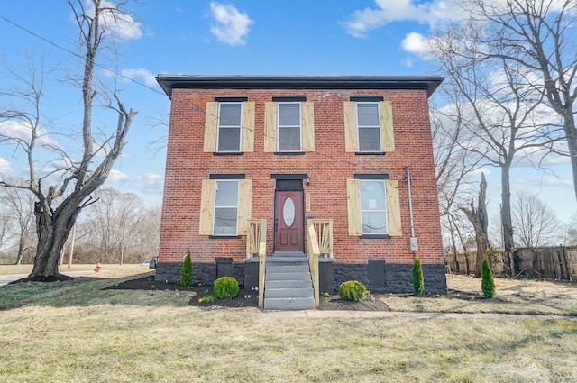 view of front of house with brick siding, a front yard, and fence