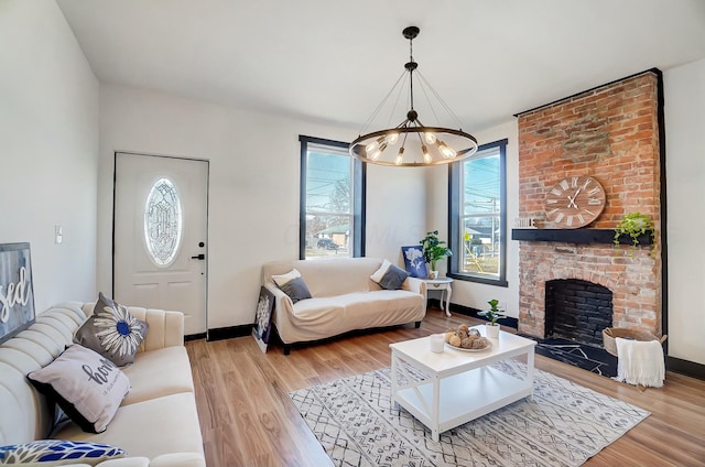 living area featuring baseboards, a brick fireplace, and light wood finished floors